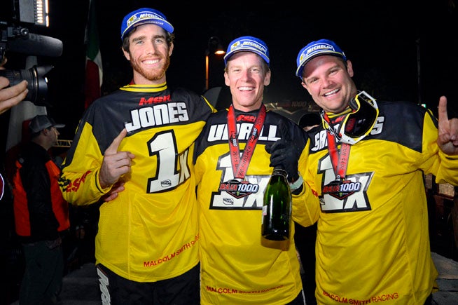 (Left to right) Justin Jones, Colton Udall and Mark Samuels celebrated their new SCORE World Desert Championship in style on the Baja 1000 podium in 2015. PHOTO BY SCOTT ROUSSEAU.
