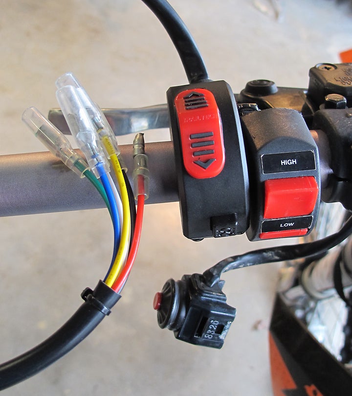 I preferred the handle-bar mounting and sturdier construction of Trail Tech’s 3-way switch with integrated kill-button.  (Stock kill-button dangles below.)