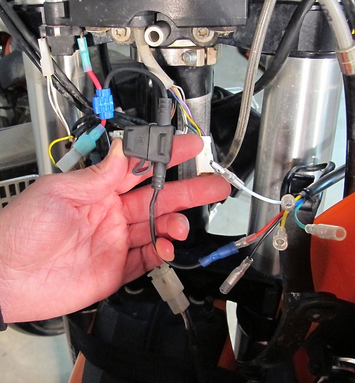 Weather-proof inline fuse holder provides insurance against excessive current and short circuits.  It’s connected to red wire from switch, and spliced into short new red wire inserted between two stock connectors in headlight circuit (yellow wire above thumb).  Entire setup is easily removed, returning bike to stock.