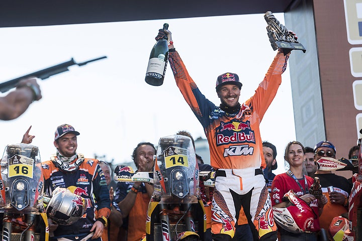 Sam Sunderland hoists the big bottle of bubbly in Buenos Aires, Argentina, to celebrated his first career Dakar Rally win. The Brit DNF'd in his last two Dakar attempts, but it all came good in 2017. PHOTO COURTESY OF RED BULL CONTENT POOL.