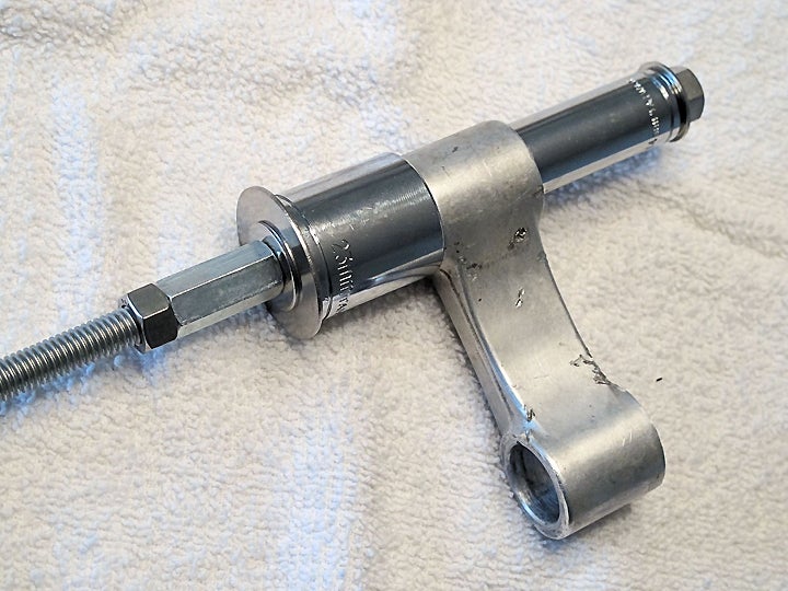 Here’s our all-thread bearing tool, clamped onto the linkage dog-bone. The narrow socket is set to press the bearings out into the wider socket braced against the dog-bone. We used a long all-thread connector as our second nut on the left side; the increased surface area made holding it still a bit easier.
