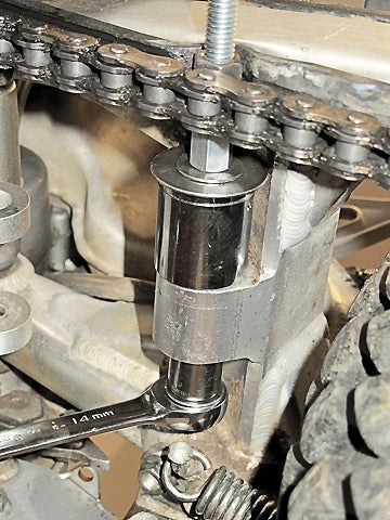 Here’s our tool in action on the swingarm boss. As that wrench gets turned, the bearings are pressed from the far side into the near socket. The whole thing must be held still at the all-thread connector, visible just inboard of the chain. To maximize visibility, the wrench for holding it isn’t shown here.